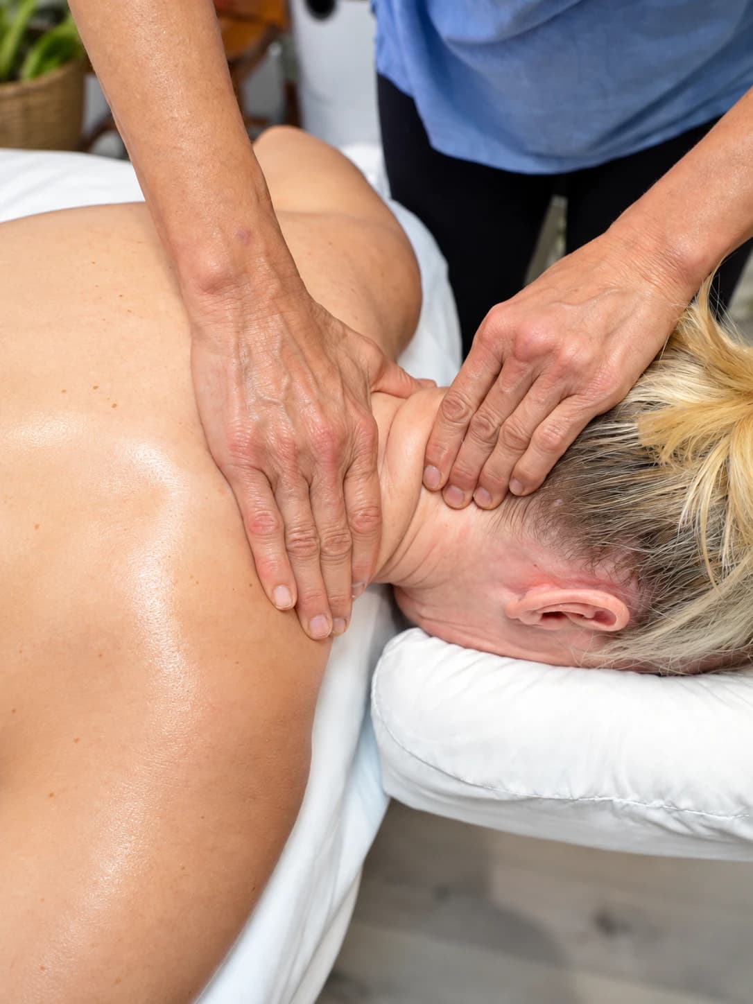 Both of a therapist’s hands working along the neck and shoulder