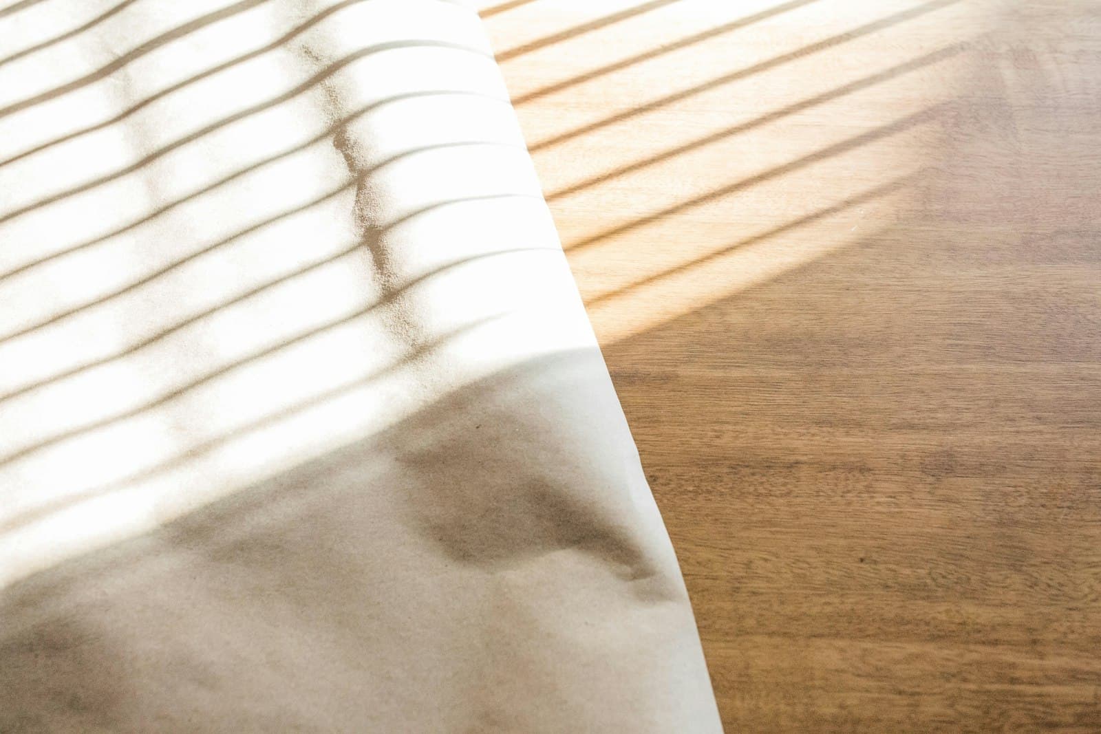 Soft window light falling across a white sheet on a wooden table