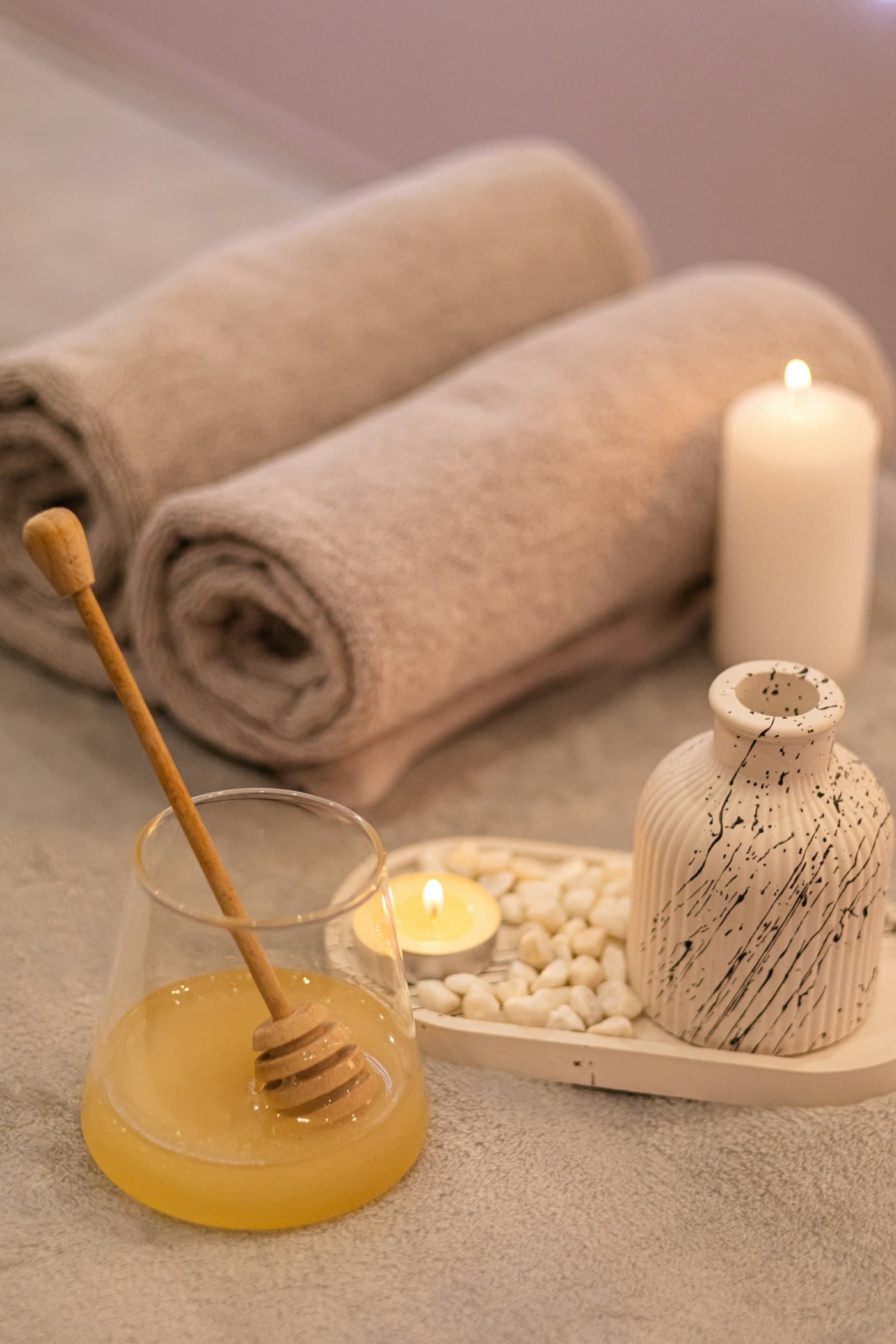 Rolled towels, a lit candle and smooth stones in warm light